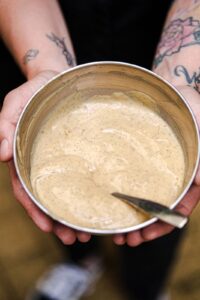 Image d’une crème pâtissière onctueuse dans un bol, avec une cuillère en bois et des ingrédients frais (œufs, lait, vanille) en arrière-plan, illustrant une recette simple et gourmande.